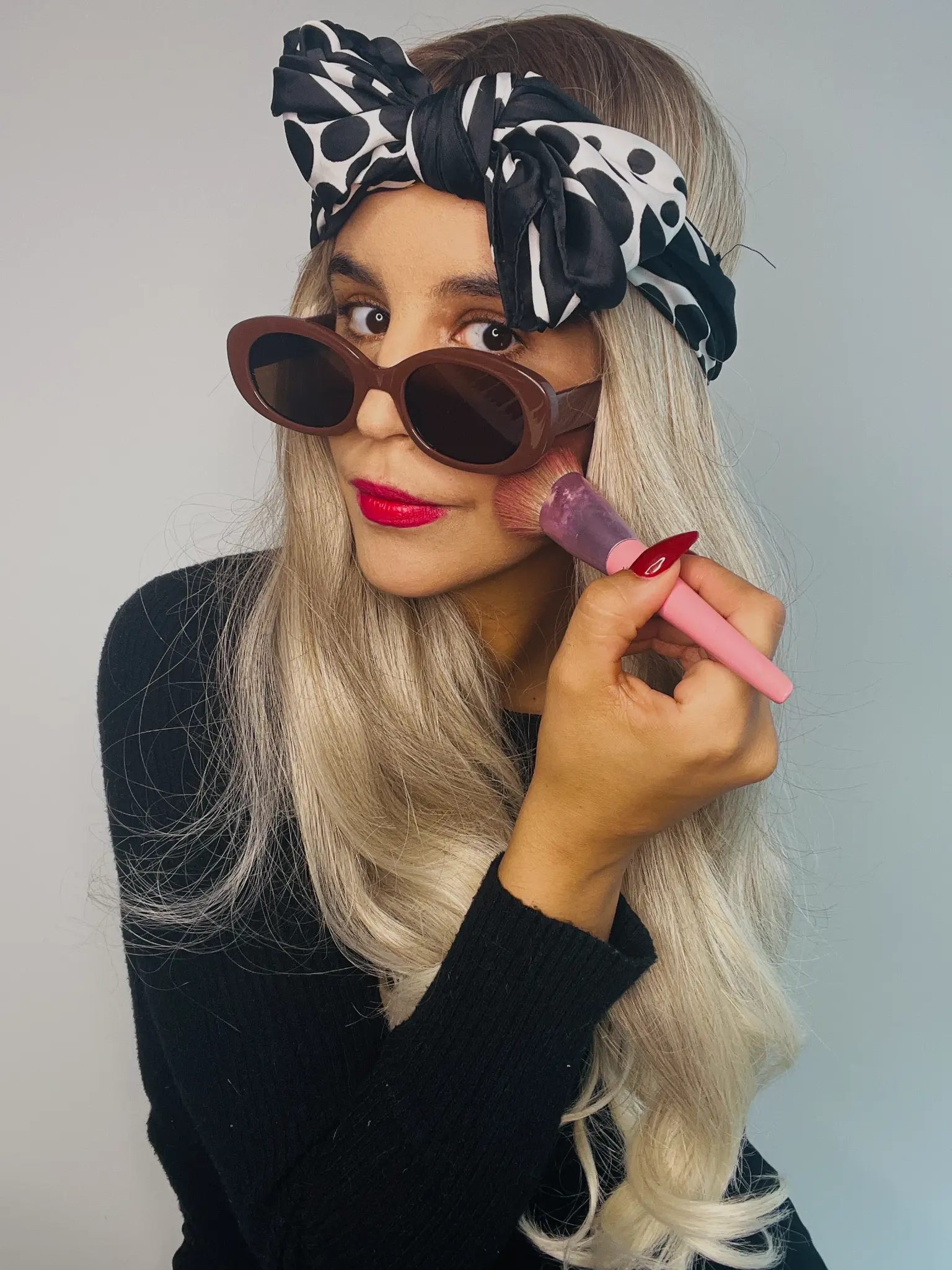 Portrait with a patterned headscarf and a makeup brush
